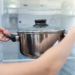 donna che mette pentola in frigo
