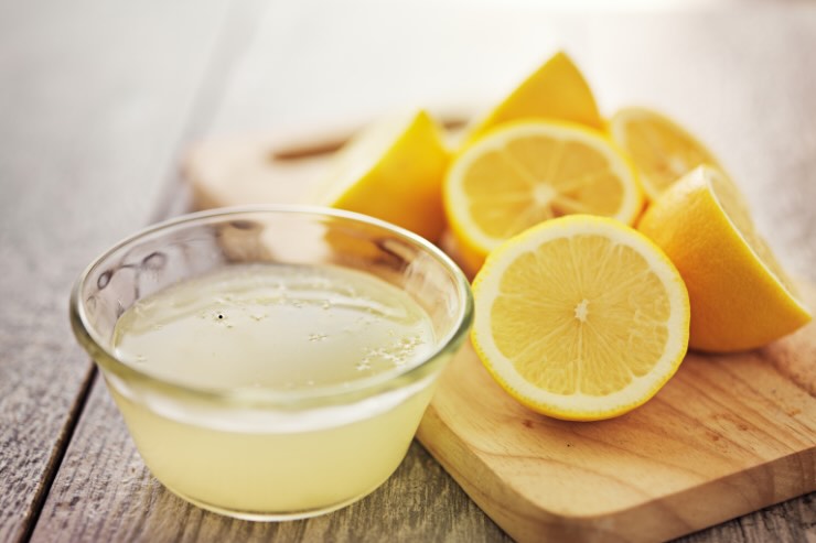scodella con succo di limone e due metà di un limone