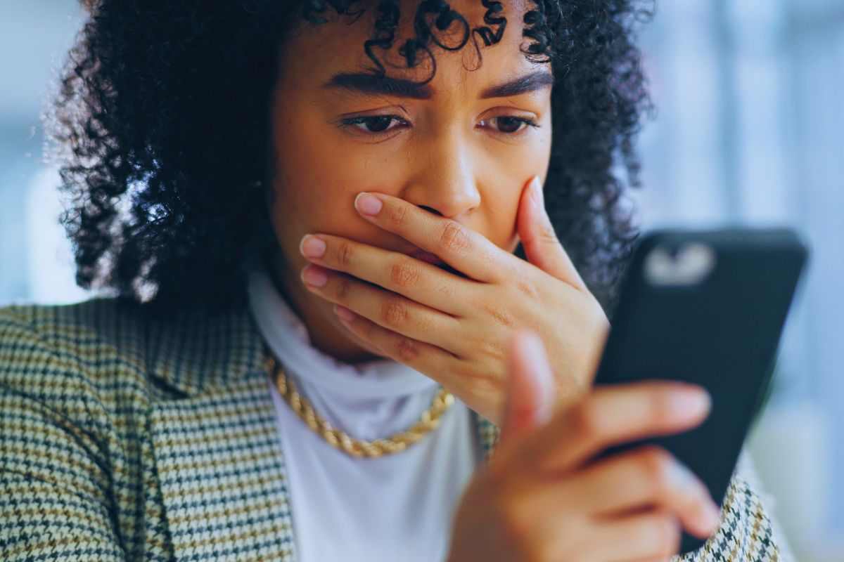 Donna con espressione sconvolta mentre guarda qualcosa su smartphone
