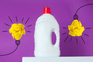 Flacone di sapone sopra alla lavatrice e due lampadine disegnate
