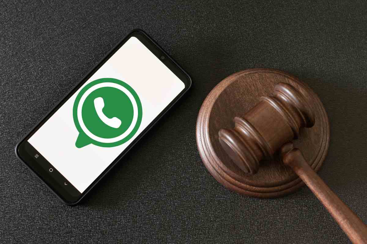 Cellulare con sfondo WhatsApp e martello del giudice in tribunale