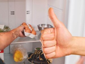 sfondo persona prende uova dal frigo e mano con pollice in su