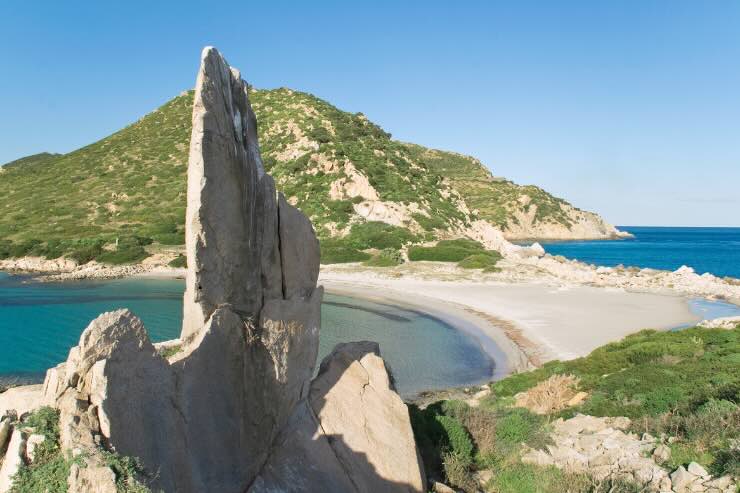 scoglio caratteristico con sfondo di mare, sabbia e vegetazione