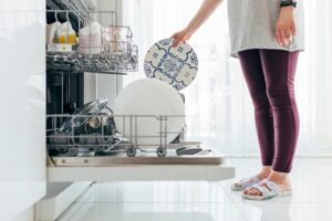 donna che mette un piatto dentro alla lavastoviglie