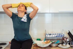 Donna in cucina con piatti sporchi