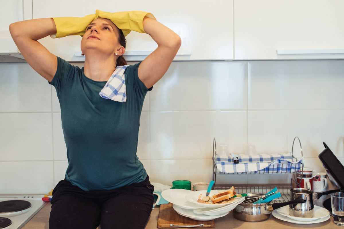 Donna in cucina con piatti sporchi