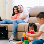 genitori seduti sul divano che guardano i figli che giocano