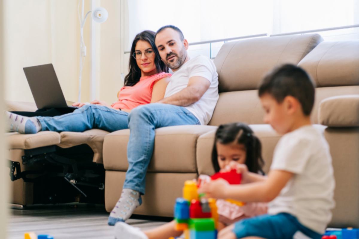 genitori seduti sul divano che guardano i figli che giocano
