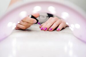 Persona che mette gel fucsia alle unghie