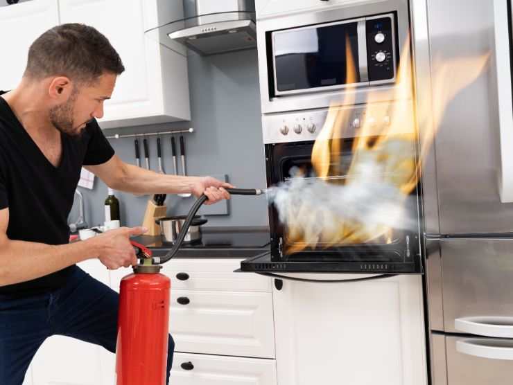 uomo che spegne incendio nel forno