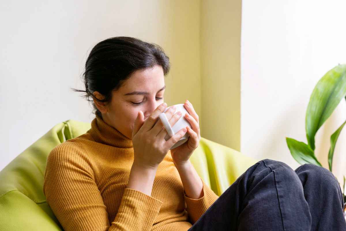 Donna che beve tisana sul divano