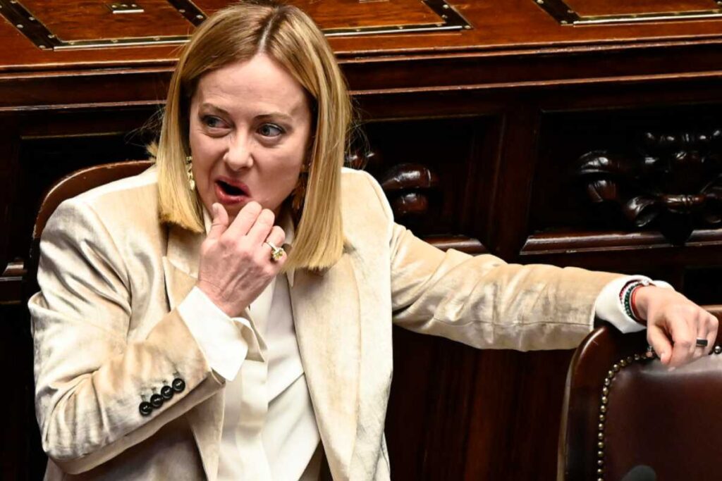il premier giorgia meloni seduta che con una mano si tocca la bocca