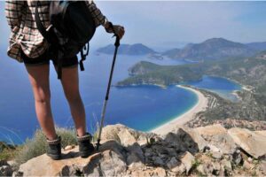 Donna abbigliamento da trekking con bastone osserva il mare da un'altura