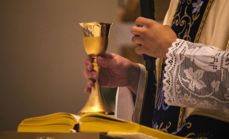 sacerdote con calice in chiesa e bibbia davanti