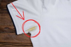 Macchia gialla di sudore nella parte delle ascelle di una maglia bianca