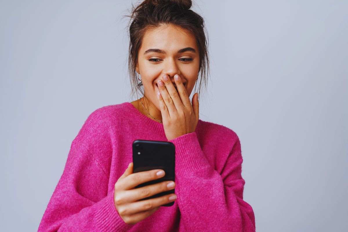 Ragazza con espressione sorpresa mentre guarda smartphone