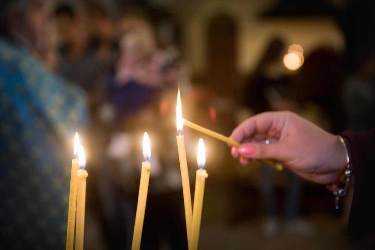 persona accende candela in chiesa
