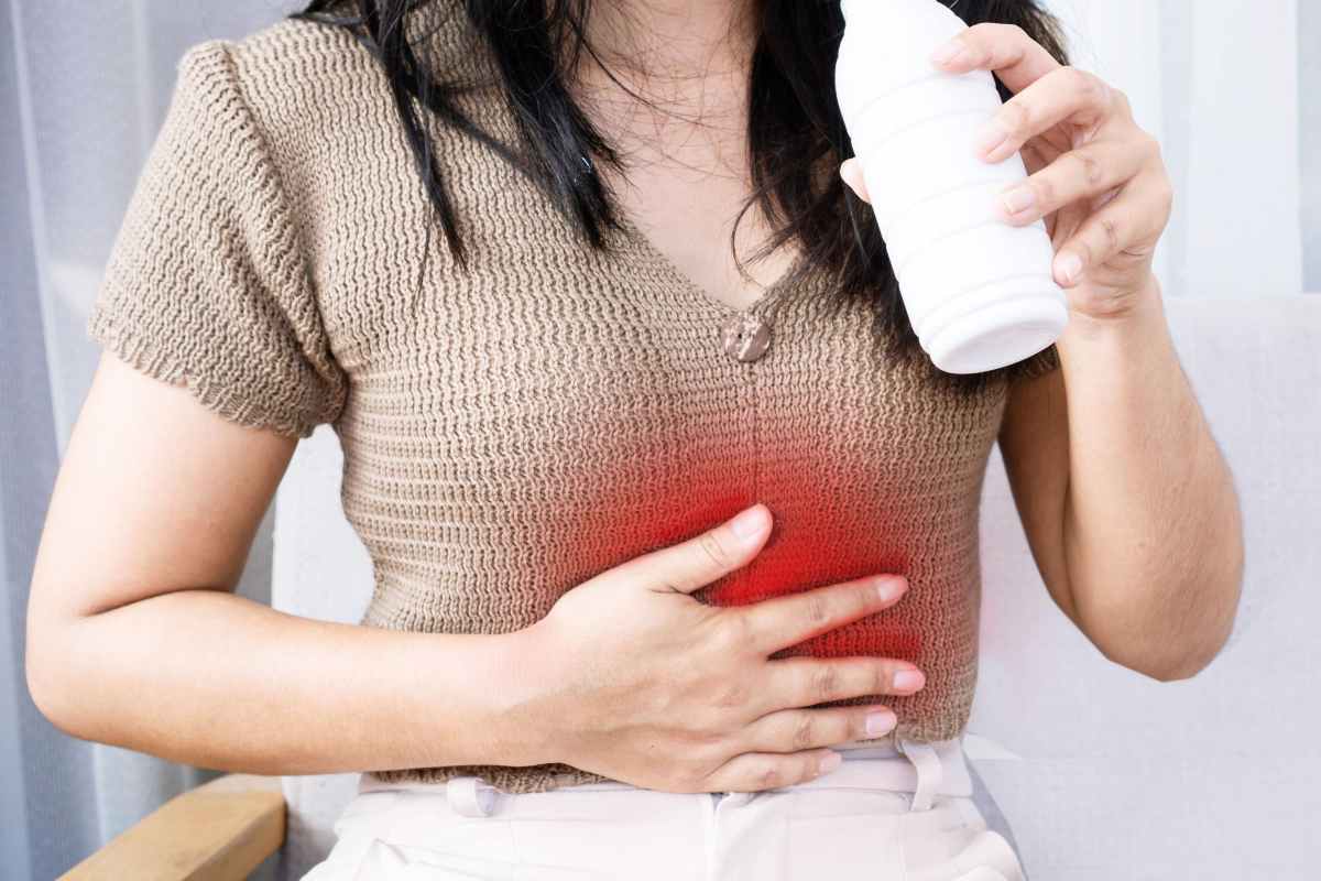 Ragazza con mano sullo stomaco e una bottiglietta in mano