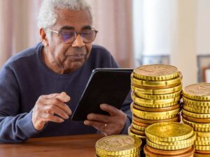 sfondo anziano che guarda tablet e monete euro