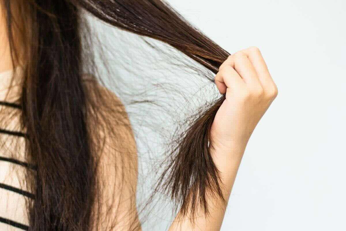 donna che si tocca una ciocca di capelli castani