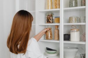 Donna che posa gli ingredienti nella dispensa
