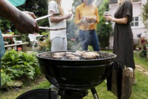Uomo che prepara un barbecue accanto a un gruppo di persone
