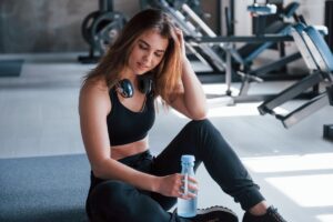 Ragazza seduta in palestra con l'aria stanca
