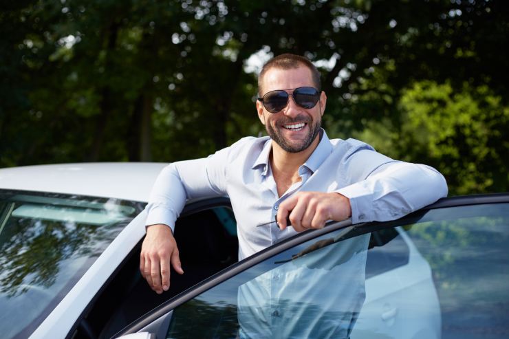 uomo sorridente con la propria auto