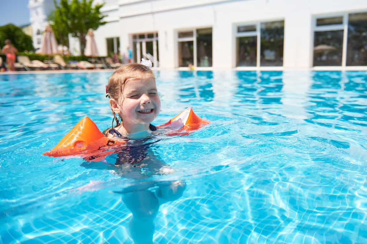 Bambina in piscina con i braccioli