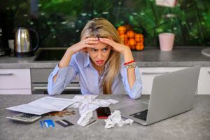 donna preoccupata con davanti pezzi di carta monete carte e pc