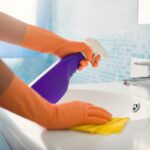 donna con guanti pulisce lavandino bagno