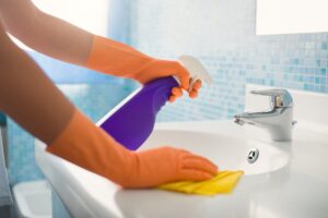 donna con guanti pulisce lavandino bagno