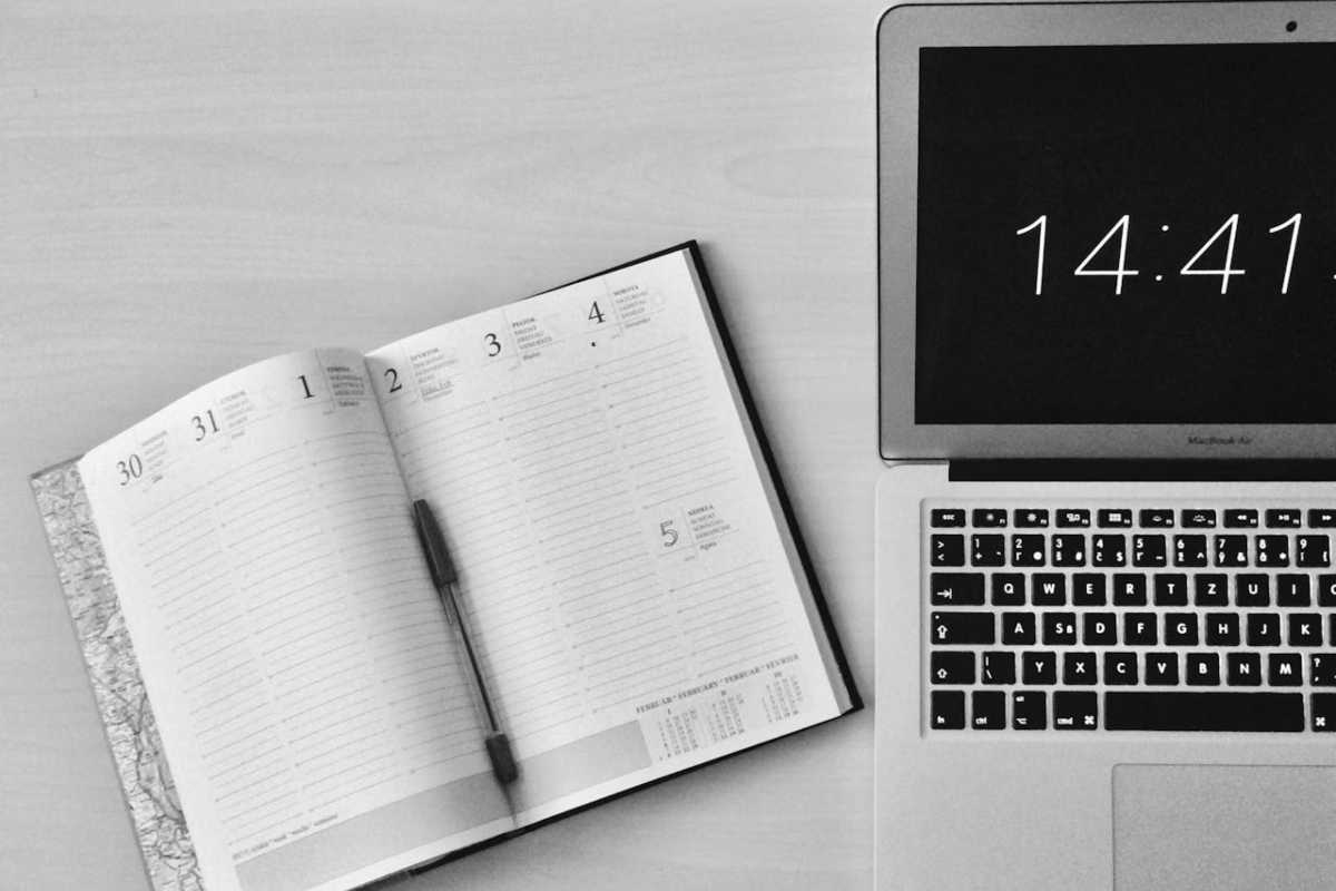 Agenda aperta accanto a laptop con orario