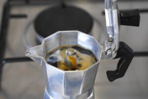 Caffettiera sul fuoco con coperchio aperto e caffè salito