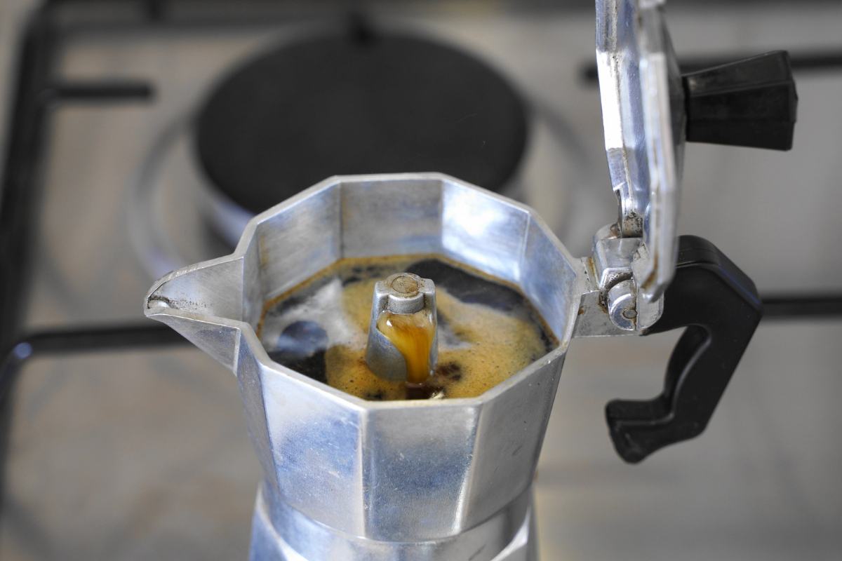 Caffettiera sul fuoco con coperchio aperto e caffè salito