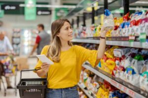 Donna che prende confezione da uno scaffale al supermercato