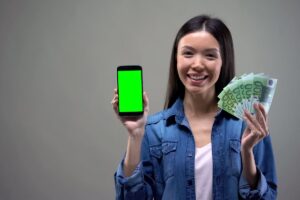 donna con cellulare e banconote da 100 euro in mano