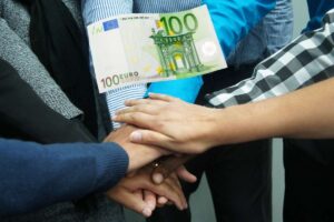 mani che si toccano per festeggiare e banconota da 100 euro