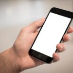 cellulare con schermo bianco tenuto in mano