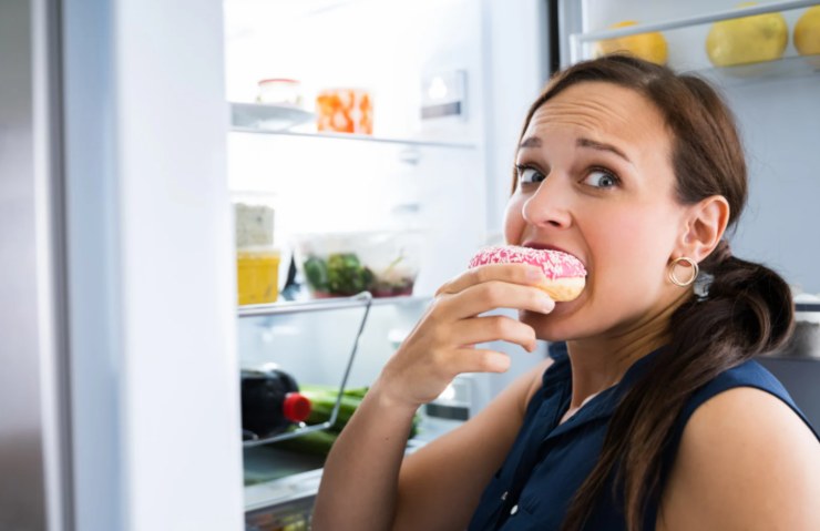 donna che apre il rigo e mangia una ciambella zuccherata