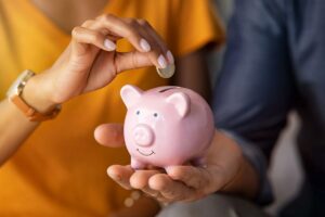 Persona che mette una moneta di un euro in un salvadanaio
