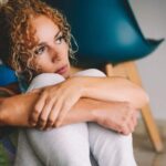 Donna triste che si abbraccia le ginocchia