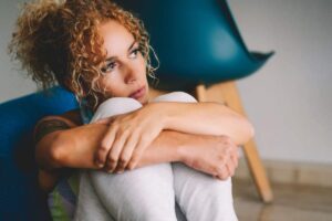 Donna triste che si abbraccia le ginocchia