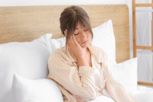 Donna sdraiata nel letto con una mano sul viso